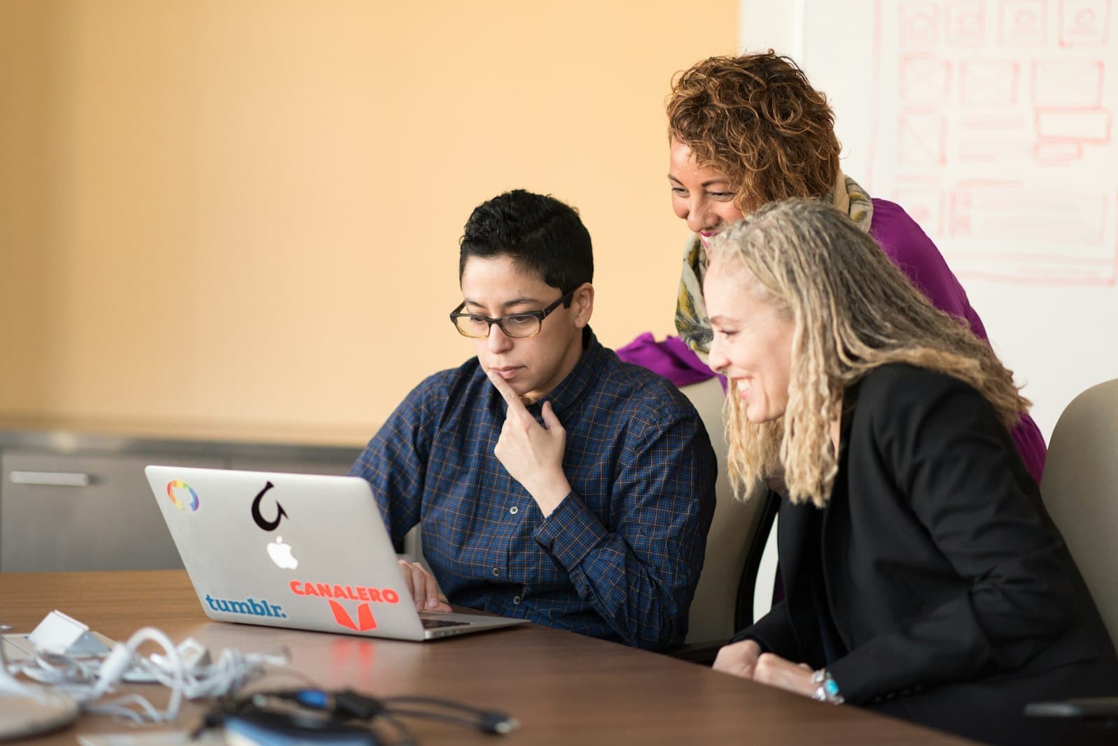 Three professionals discussing over a tablet in a modern office setting